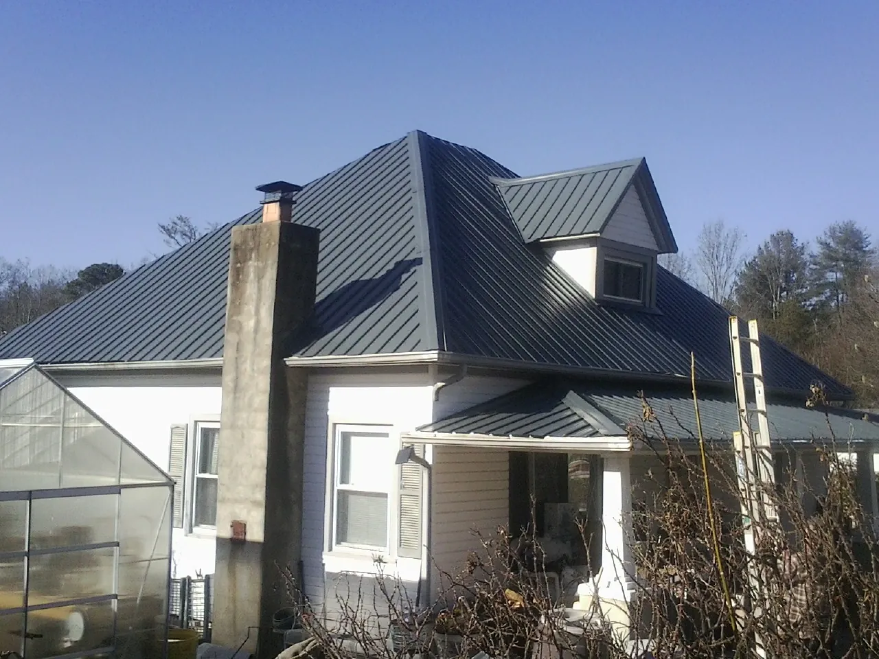 Dark blue standing seam metal roof on a white farmhouse with dormer — Slate & Tile Roof Repair by Roofing Brothers in Kenneth