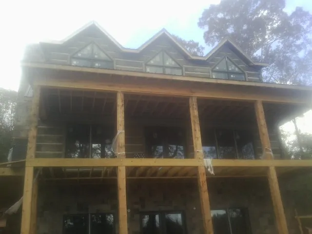 Dormers and porch framing on a large log home under construction — Roof Coating work by our crew in Kenneth