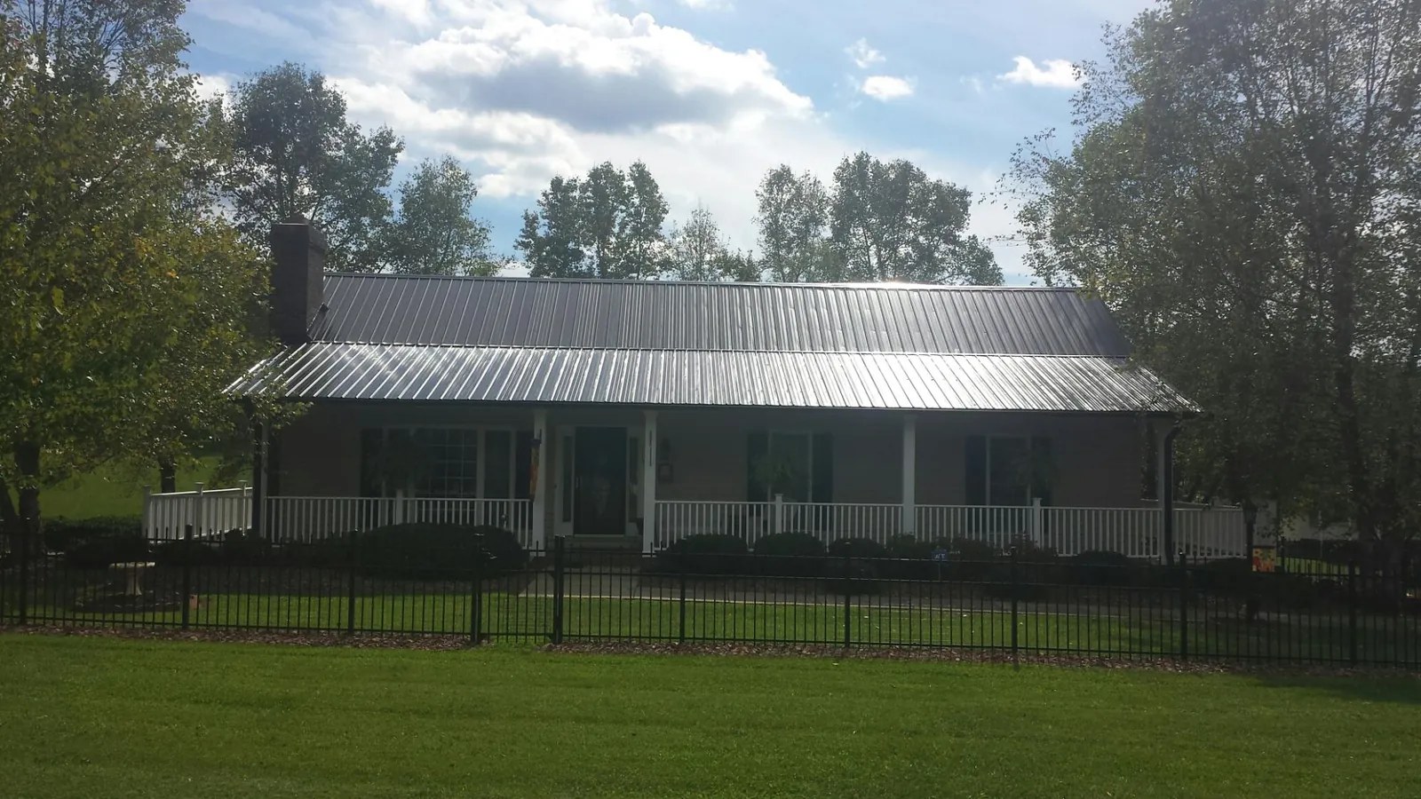 Gray metal roof on a brick ranch with a full width front porch — Gutter Guard Installation work by our crew in Kenneth